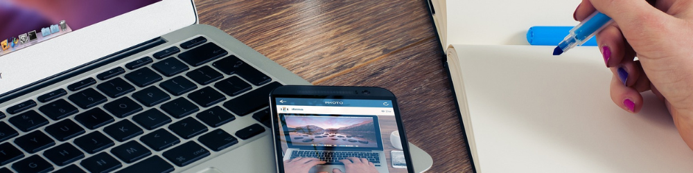 cell phone on a laptop with a hand holding a marker