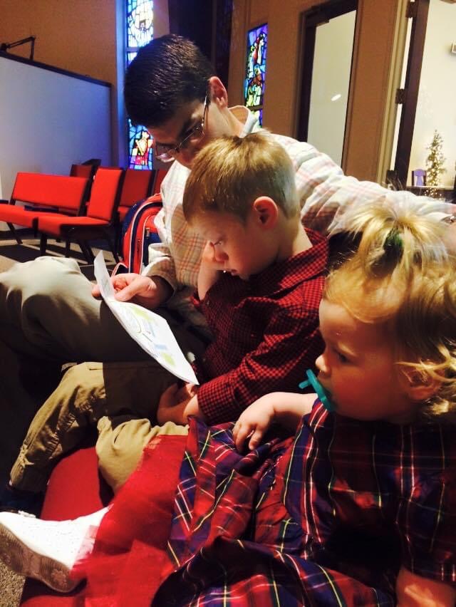 Image of father with son and daughter in the back pew of a church at Christmas.