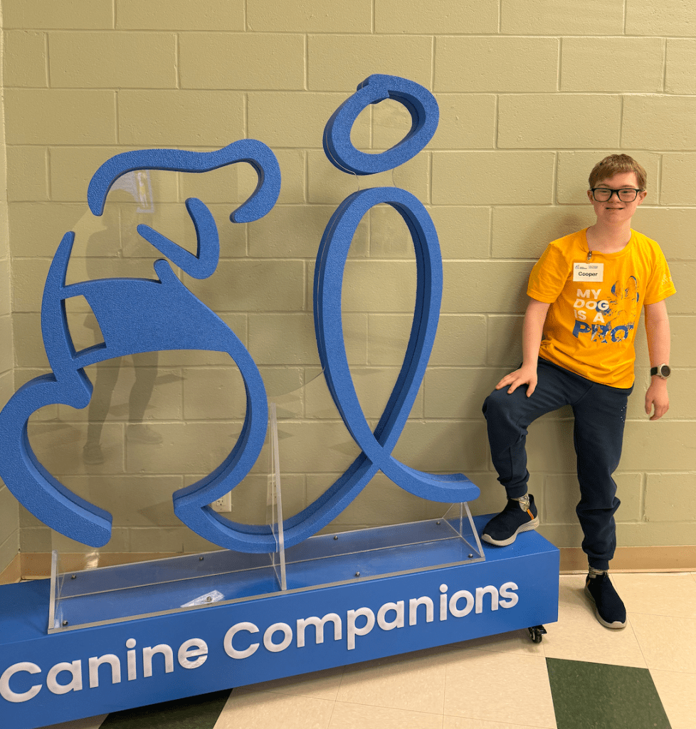 Boy standing next to the Canine Companions sign