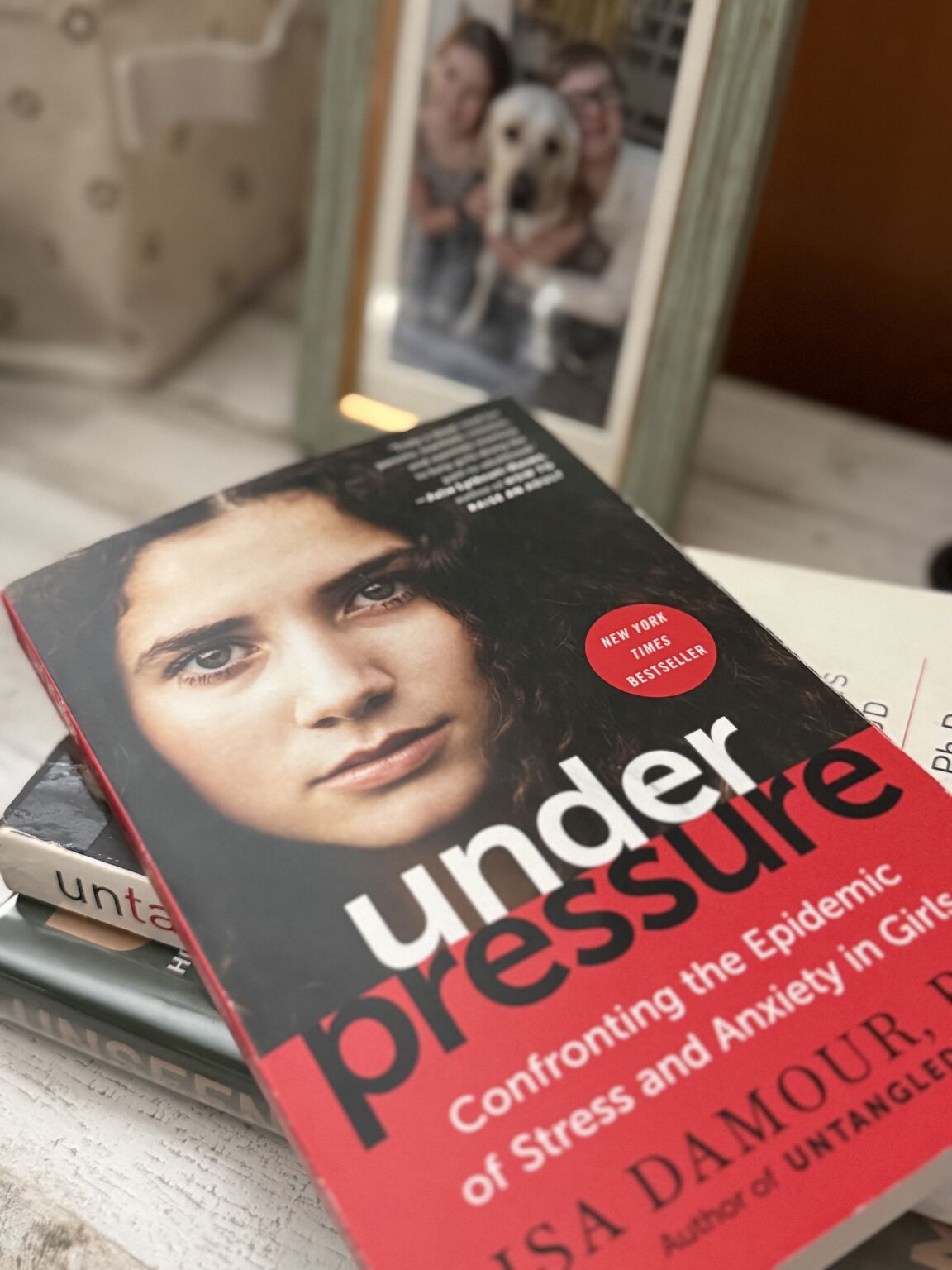 Under Pressure by Lisa Damour on a pile of books on a desk